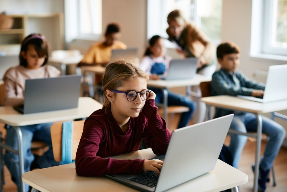 Student using a refurbished laptop in a school library setting.